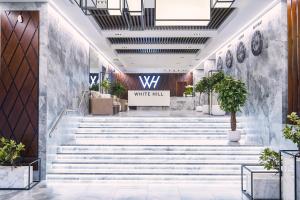 a lobby with stairs and a sign that reads white rule at WHITE HILL Hotel in Belgorod