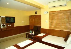 a room with two beds and a window with a tv at Arudhra Residency in Chidambaram