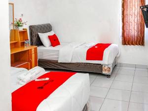duas camas num pequeno quarto com lençóis vermelhos e brancos em RedDoorz near Reremi Pemancar Manokwari em Manokwari
