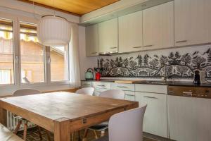 cocina con mesa de madera y armarios blancos en Baldrian C14, en Adelboden