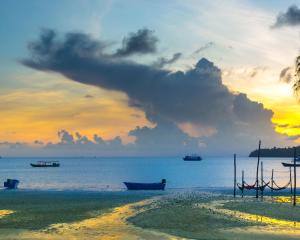 a beach with boats in the water at sunset at Sara Resort in Koh Rong Sanloem
