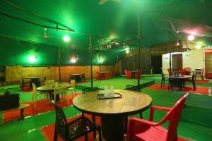 een kamer met tafels en stoelen en groene verlichting bij Le Apex Home Stay in Auroville