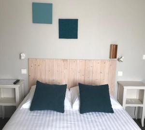 a bed with two blue pillows and two tables at Hôtel la petite auberge in Arès