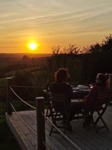 dos personas sentadas en una mesa viendo la puesta de sol en Looe Yurts en Looe
