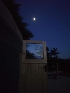 a moon over a house with a window at night at Looe Yurts in Looe