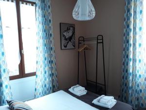 een slaapkamer met een bed met blauwe gordijnen en een raam bij Hôtel Ambroise in Uzerche