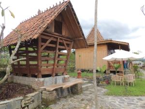 Bedakah的住宿－Singgasana Villa & Resto，一座带长凳和遮阳伞的木制建筑