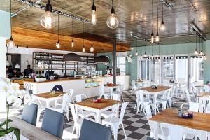 a restaurant with white tables and chairs and a counter at Tenbergen Pension Hotel in Windhoek