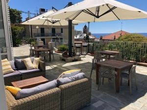 patio con divani, tavoli e ombrellone di MH HOTEL VARAZZE a Varazze