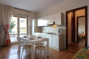 a kitchen with a table and chairs and a kitchen with white cabinets at Villa Stefano in Bibione
