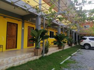 uma casa com paredes amarelas e um carro estacionado em frente em เพลินเพลิน​ วิลล่า em Sattahip