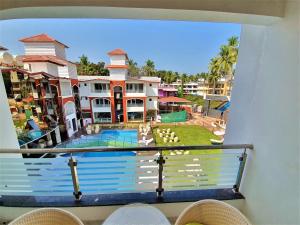balcón con vistas a la piscina y a las casas en VITS Shanti Solitaire, Arpora, en Arpora