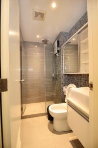 a bathroom with a shower and a toilet and a sink at Malate Bayview Mansion city view in Manila
