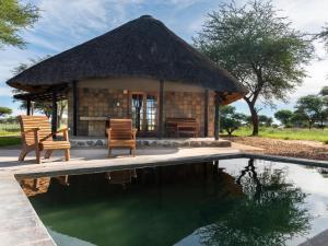 a hut with two chairs and a swimming pool at Africa Awaits Lodge & Safaris in Gobabis