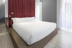 a white bed in a room with a red headboard at B&B HOTEL Madrid Centro Fuencarral 52 in Madrid