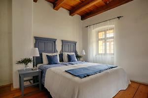 um quarto com uma cama com uma cabeceira azul e uma janela em Zuzmó Guesthouse, Jósvafő, Aggtelek National Park - Stylish 150 year old farmhouse for 10 guests em Jósvafo