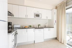 ロザスにあるApart-rent Apartment Francesc Macia Penthouse 2000の白いキッチン(白いキャビネット、電子レンジ付)