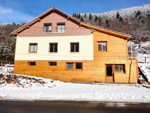 une grande maison en bois avec de la neige au sol dans l'établissement Gite de L'ours, à La Bresse