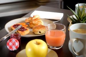a plate of pastries and an apple and a glass of orange juice at Hotel de Champagne in Épernay +115 photos
