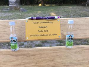 dos botellas de agua sentadas en un banco con un cartel en Heidetraum Pension & Ferienwohnung Arndt, en Bispingen