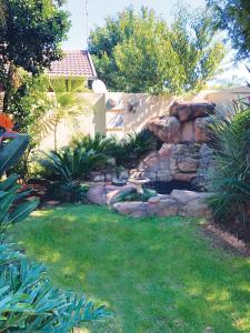 a backyard with a stone wall and a yard at African BnB - The Boutique Experience in Benoni
