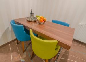 una mesa de madera con sillas y un bol de fruta. en Holiday Home Aparthotel, en Międzyzdroje