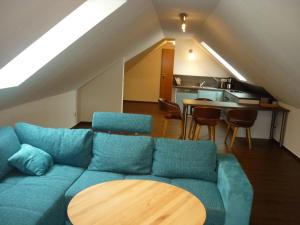 Pension Dachgeschosswohnung في Bastorf: غرفة معيشة مع أريكة زرقاء وطاولة