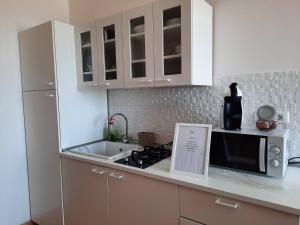 kuchnia z białymi szafkami, zlewem i kuchenką mikrofalową w obiekcie Aloha Marzamemi Rooms w mieście Marzamemi +29 zdjęć