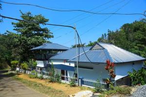 a white house with a tin roof on a street at Eden Homestay Idukki in Idukki