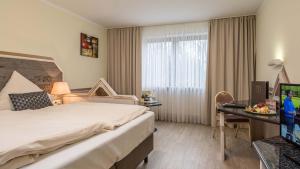 una camera d'albergo con letto, scrivania e TV di Hotel am Schlosspark a Ismaning