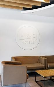 une salle d'attente avec des canapés et un panneau mural dans l'établissement B&B HOTEL Donostia Aeropuerto, à Oiartzun