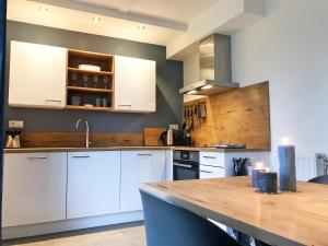 a kitchen with white cabinets and a wooden counter top at Vakantiehuis Sonnewende in Veere