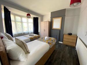 a bedroom with two beds and two windows at Exton House -Huku Kwetu 4 Bedroom House- Luton Airport - Group Accommodation - up to 7 people in Luton