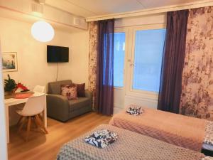 a room with two beds and a couch and a desk at Patria apartments in Lahti