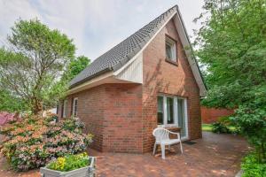 a brick house with a white chair on a patio at Landhaus Braband Ferienhaus - Rugenbargsweg 23 in Cuxhaven