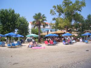 a group of people sitting in chairs and umbrellas on a beach at Hercules Sea Front Studios in Katelios