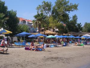 a group of people sitting on a beach with umbrellas at Hercules Sea Front Studios in Katelios