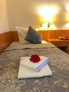 a red rose on a pile of towels on a bed at Hotel Kaiser in Mönchengladbach