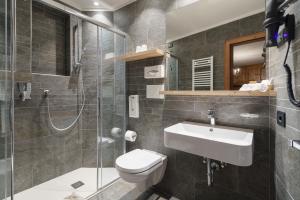 łazienka z toaletą, umywalką i prysznicem w obiekcie Hotel Columbia & Spa w mieście Cortina dʼAmpezzo +37 zdjęć