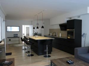 a kitchen with black cabinets and a bar with stools at ApartmentInCopenhagen Apartment 936 in Copenhagen