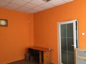 Dieses orangefarbene Zimmer verfügt über einen Schreibtisch und eine Glastür. in der Unterkunft Andrea Vendégház Székesfehérvár in Székesfehérvár