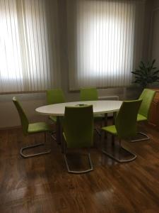 een vergaderzaal met een tafel en groene stoelen bij Andrea Vendégház Székesfehérvár in Székesfehérvár