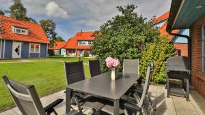 Heideröschen Park - Haus 5a في زنغست: طاولة سوداء مع كراسي و مزهرية من الزهور