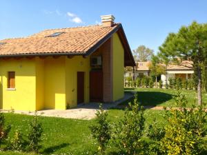 una casa amarilla con techo rojo en Casabianca Resort Villas en Lignano Sabbiadoro