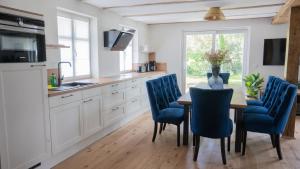 uma cozinha com uma mesa de madeira e cadeiras azuis em Haus Tadder em Born