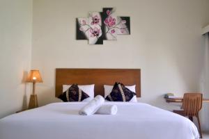 um quarto com uma cama branca e toalhas em sammy cottage senggigi em Mangsit