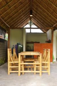 a wooden table and chairs under a roof at sammy cottage senggigi in Mangsit