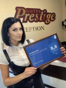 a woman is holding a laptop in a store at Hotel Prestige in Barnaul