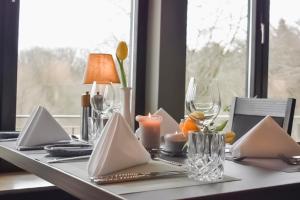 einen Tisch mit Servietten und Kerzen auf einem Tisch mit einem Fenster in der Unterkunft Bergmark Hotel in Steinfeld