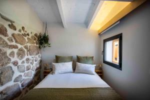 Cama en habitación con pared de piedra en Finca el Veinti9, en Navacerrada